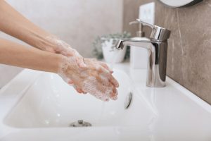 Picture of a woman washing her hands at a sink.