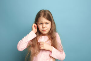 Picture of a young girl touching her ear in pain.